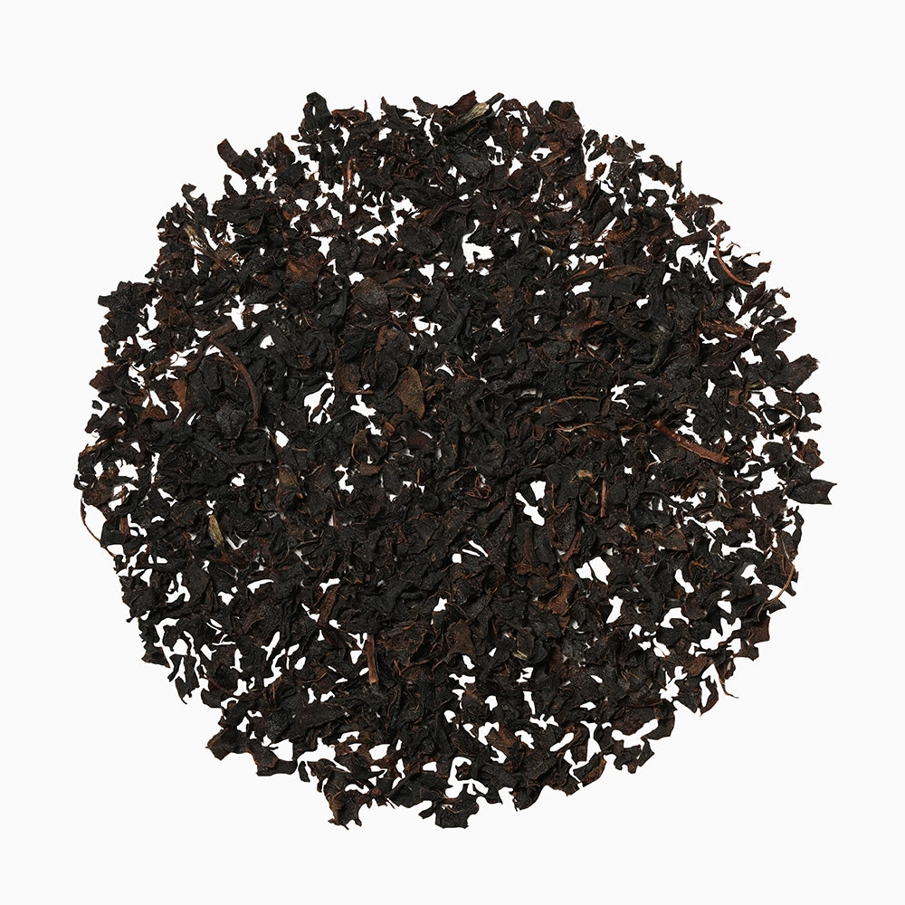 Round pile of black tea leaves — representing the Kulukkumalai blend.